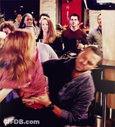 A Man And A Woman Are Sitting On A Couch In Front Of A Crowd Of People GIF