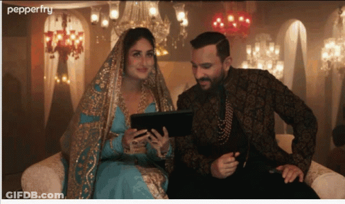 A Man And A Woman Are Sitting On A Couch Looking At A Tablet With Pepperfry Written On The Bottom GIF