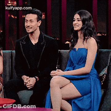 A Man And A Woman Are Sitting On A Couch . GIF
