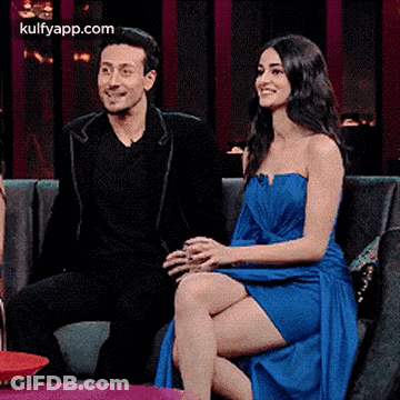 A Man And A Woman Are Sitting On A Couch Talking To Each Other . GIF