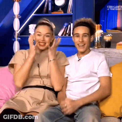 Man And Woman Sitting On Couch With Koh-Lanta Sign GIF