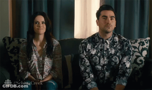 A Man And A Woman Are Sitting On A Couch With The Hashtag Schitts Creek On The Bottom GIF