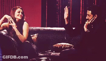 A Man And A Woman Are Sitting On A Couch With The Woman Dancing GIF
