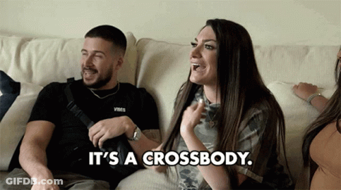 A Man And A Woman Are Sitting On A Couch With The Woman Saying It 'S A Crossbody . GIF