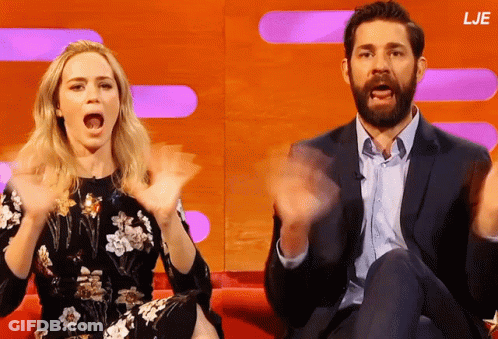 A Man And A Woman Are Sitting On A Couch With Their Hands In The Air And The Letters Lje Are On The Bottom GIF