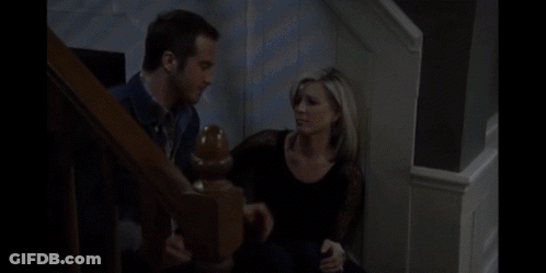 A Man And A Woman Are Sitting On A Set Of Stairs Talking To Each Other GIF