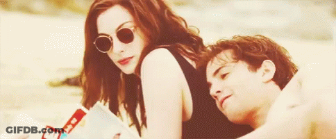 A Man And A Woman Are Sitting On The Beach . GIF