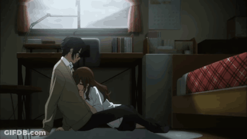 A Man And A Woman Are Sitting On The Floor Hugging Each Other GIF