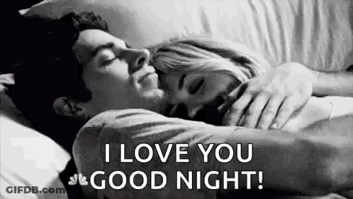 A Man And A Woman Are Sleeping In A Bed And The Man Is Hugging The Woman . GIF