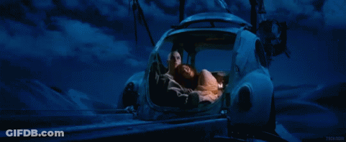 A Man And A Woman Are Sleeping In A Car With A Blue Sky Behind Them GIF