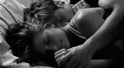A Man And A Woman Are Sleeping On A Bed . GIF