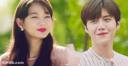 A Man And A Woman Are Smiling And Looking At The Camera GIF