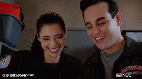 A Man And A Woman Are Smiling And Wearing A Jacket That Says Chicago Fire Department GIF