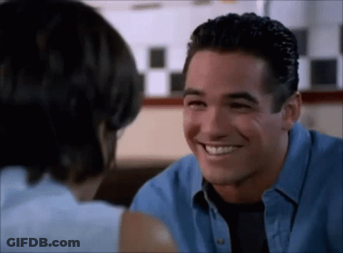 A Man And A Woman Are Smiling At Each Other While Sitting At A Table . GIF