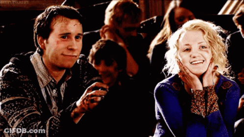 A Man And A Woman Are Smiling In Front Of A Sign That Says Rita Parley On It GIF