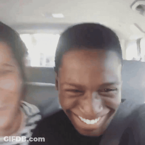 A Man And A Woman Are Smiling In The Back Seat Of A Car . GIF