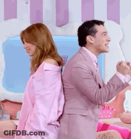 A Man And A Woman Are Standing Back To Back And The Woman Is Wearing A Pink Shirt . GIF