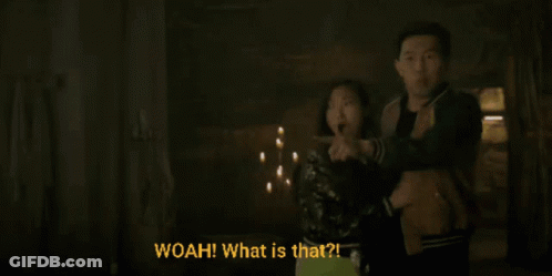 A Man And A Woman Are Standing In A Dark Room And The Woman Is Pointing At Something And The Man Is Saying Woah What Is GIF