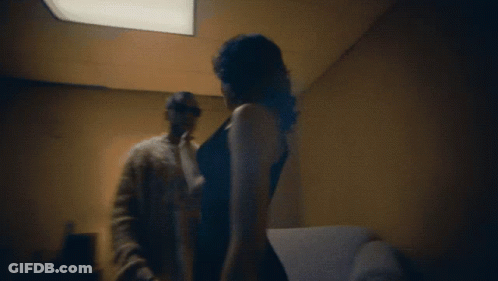 A Man And A Woman Are Standing In A Dark Room GIF