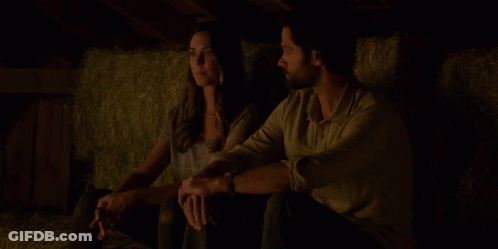 A Man And A Woman Are Standing In A Dark Room With A Light On The Ceiling GIF