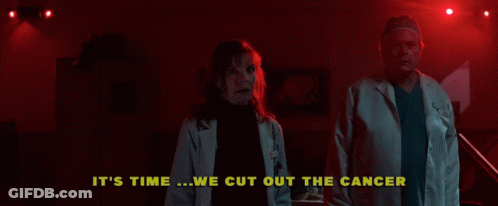 A Man And A Woman Are Standing In A Dark Room With The Words " It 'S Time We Cut Out The Cancer " Above Them GIF
