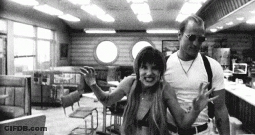 A Man And A Woman Are Standing In A Diner . GIF