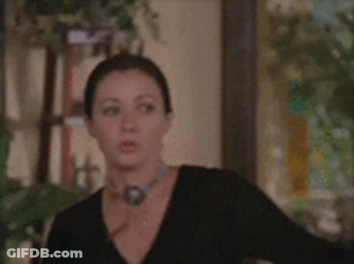 A Man And A Woman Are Standing In A Hallway Looking At A Door GIF