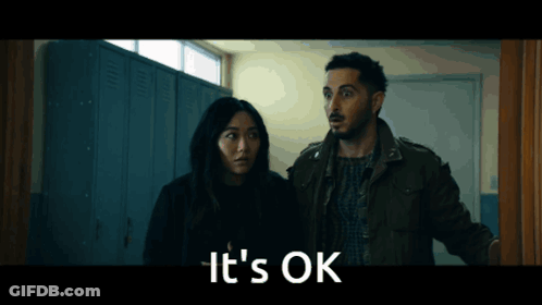 A Man And A Woman Are Standing In A Hallway With The Words " It 'S Ok " On The Bottom GIF