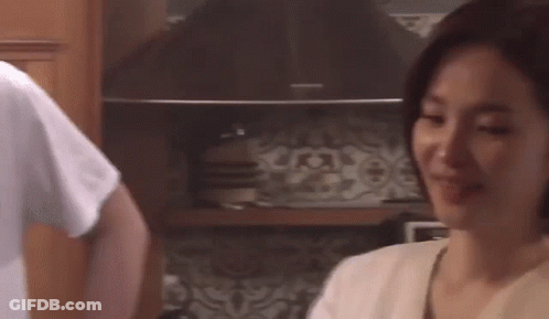 A Man And A Woman Are Standing In A Kitchen . GIF