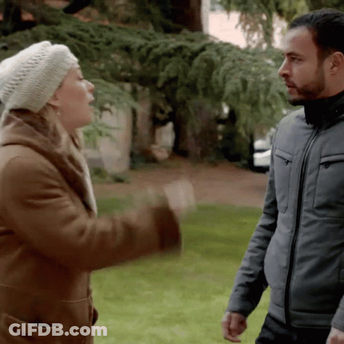A Man And A Woman Are Standing In A Park GIF