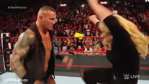 A Man And A Woman Are Standing In A Wrestling Ring . GIF