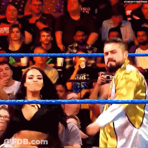 A Man And A Woman Are Standing In A Wrestling Ring With A Crowd Watching . GIF
