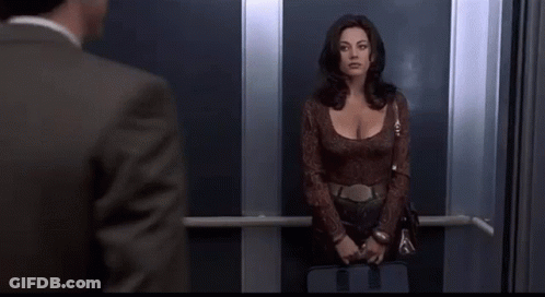 A Man And A Woman Are Standing In An Elevator . GIF