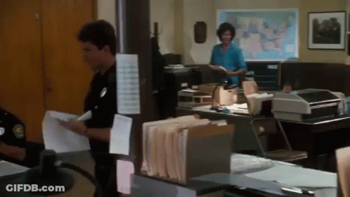 A Man And A Woman Are Standing In An Office With A Map Of The United States In The Background GIF