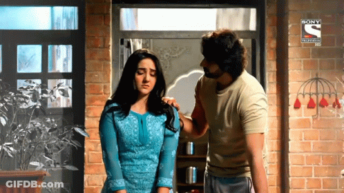 A Man And A Woman Are Standing In Front Of A Brick Wall And A Sign That Says Sony Television GIF