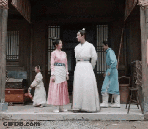A Man And A Woman Are Standing In Front Of A Building GIF