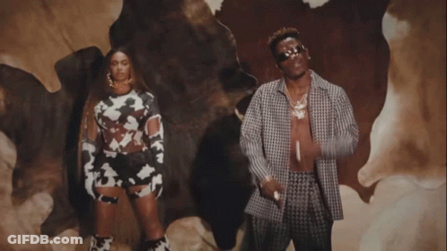 A Man And A Woman Are Standing In Front Of A Cow Skin GIF