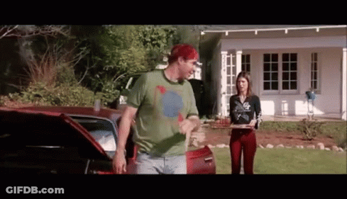 A Man And A Woman Are Standing In Front Of A House . GIF