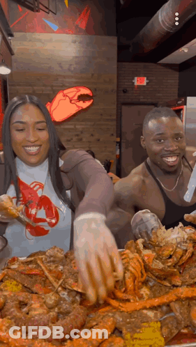 A Man And A Woman Are Standing In Front Of A Large Plate Of Food .. GIF