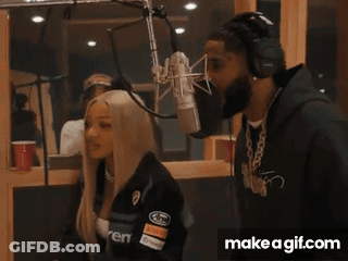 A Man And A Woman Are Standing In Front Of A Microphone With Make A Gif.com In The Corner GIF