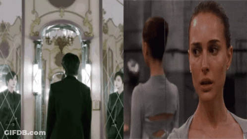 A Man And A Woman Are Standing In Front Of A Mirror And Looking At Each Other GIF