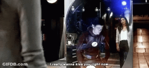 A Man And A Woman Are Standing In Front Of A Mirror . GIF