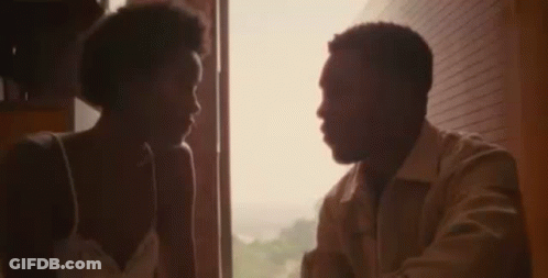 A Man And A Woman Are Standing In Front Of A Mirror Looking At Each Other . GIF