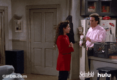 A Man And A Woman Are Standing In Front Of A Refrigerator That Says Seinfeld GIF