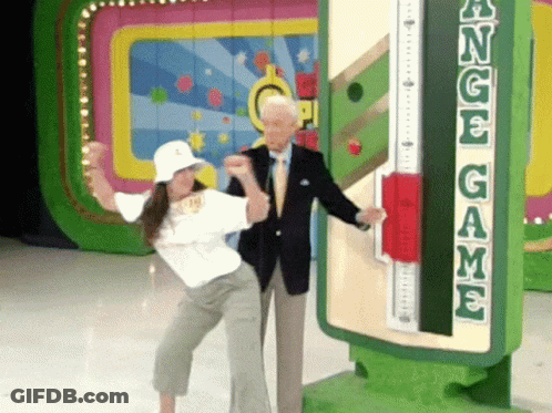 A Man And A Woman Are Standing In Front Of A Sign That Says Angel Game GIF