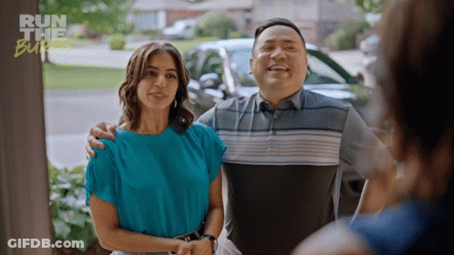 A Man And A Woman Are Standing In Front Of A Sign That Says Run The Burger GIF