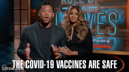 A Man And A Woman Are Standing In Front Of A Sign That Says " The Covid-19 Vaccines Are Safe " GIF