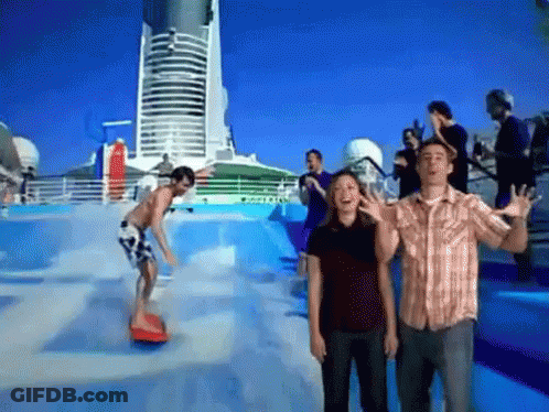 A Man And A Woman Are Standing In Front Of A Wave Pool While A Man Rides A Surfboard GIF