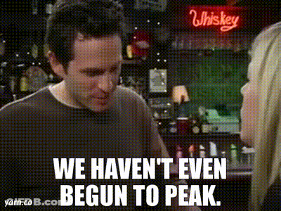 A Man And A Woman Are Standing In Front Of A Whiskey Sign And Talking To Each Other . GIF