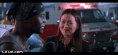 A Man And A Woman Are Standing In Front Of An Ambulance . GIF